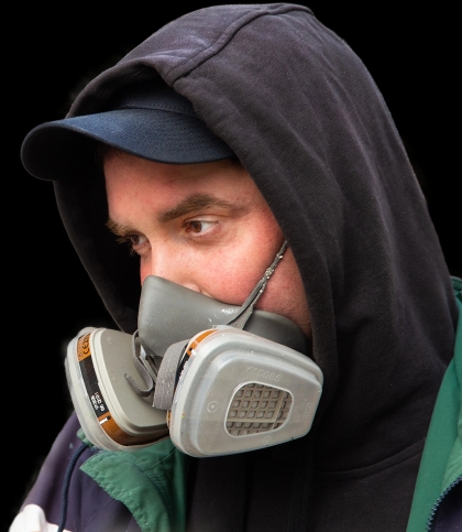 Jon Gredmark wearing a respirator mask and a hoodie, focusing on his task